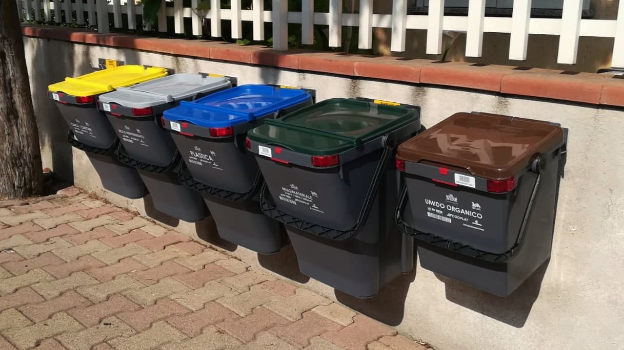 una serie di contenitori per la raccolta differenziata, appesi con il supporto EcoBlock System